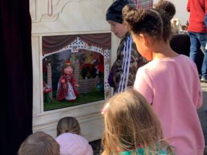 Children sitting in front of puppet stage at New Bern Mardi Gras Festival and Parade 2023